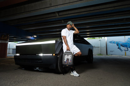 cybertruck pictured with a man holding a black and gold noir luxe backpack 